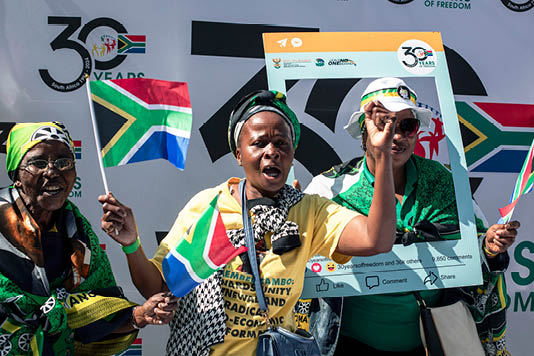 PRETORIA SOUTH AFRICA APRIL 27: Women carry South African flags as they celebrate 30 years of freedom at Union Buildings on April 27, 2024, in Pretoria, South Africa. The country is marking 30 years since its first democratic elections, held in April 1994 after decades of white minority rule that denied Black people the right to vote. The country's next general election will be held on May 29, amid pervasive economic challenges. (Photo by Per-Anders Pettersson/Getty Images)