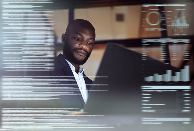Shot of a young man programmer using a laptop while working late in their office