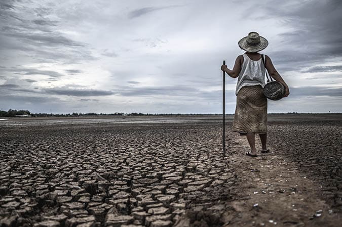 Women standing on dry soil and fishing gear, global warming and water crisis
