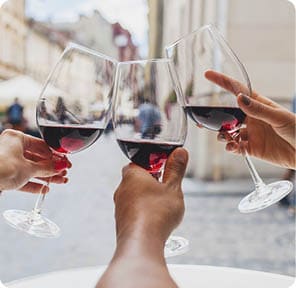 young hipster company of friends sitting in city street cafe, close up hands holding glasses, toasting, celebrating, drinking wine, summer vacation, party, having fun, details