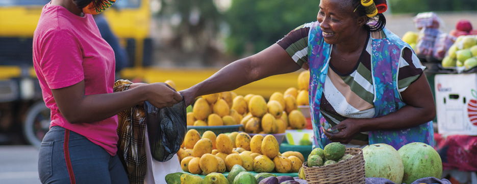 An African American female in a protective face mask shopping for fruit at a market