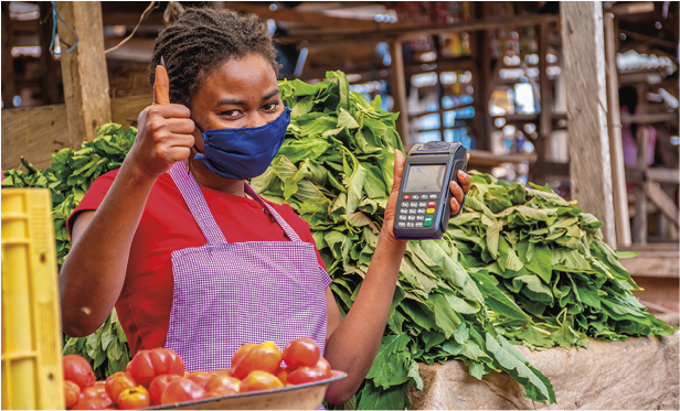 A shallow focus of an African female with a facemask holding a POS machine at a market